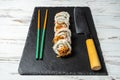 Group of fresh sushi with wooden chopsticks on a black stone plate board and on a white rusty background.Soft focus shot Royalty Free Stock Photo