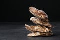 A group of freshly and raw shucked oysters on a black background. Chilled raw oysters. Delicious tropical sea mollusk.