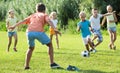 Group of friendly kids playing football together on green lawn in park Royalty Free Stock Photo