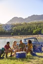 Group Of Friends With Backpacks By Pick Up Truck On Road Trip Drinking Beer From Cooler By Lake Royalty Free Stock Photo