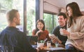 Group of friends chatting and using laptop in cafe at the coffee shop cafe in university talking and laughing together. Royalty Free Stock Photo