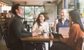 Group of friends chatting and using laptop in cafe at the coffee shop cafe in university talking and laughing together. Royalty Free Stock Photo