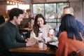 Group of friends chatting and using laptop in cafe at the coffee shop cafe in university talking and laughing together. Royalty Free Stock Photo