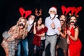 Six young funny friends, four girls and two boys while celebrating Christmas. Group of friends at club having fun. New Royalty Free Stock Photo