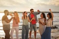 Group of friends with drinks having fun near river at summer party Royalty Free Stock Photo