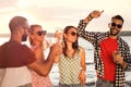 Group of friends with drinks having fun near river at summer party Royalty Free Stock Photo