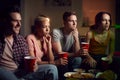 Group Of Friends With Drinks Sitting On Sofa At Home Watching Horror Movie Together