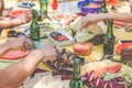 Group of friends eating dinner at barbecue party outdoor in nature - Closeup of people eating and drinking beer at picnic bbq meal Royalty Free Stock Photo