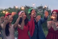 Group of friends enjoying with sparklers in the party. Selective focus on face of woman in red dress Royalty Free Stock Photo