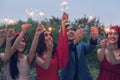 Group of friends enjoying with sparklers in the party. Selective focus on face of woman in red dress Royalty Free Stock Photo