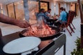 A group of friends and family barbecue together in the evening on the terrace in front of a large modern house