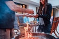 A group of friends and family barbecue together in the evening on the terrace in front of a large modern house