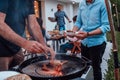 A group of friends and family barbecue together in the evening on the terrace in front of a large modern house