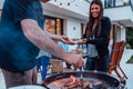 A group of friends and family barbecue together in the evening on the terrace in front of a large modern house