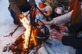 Group of friends gathering around bonfire in backyard, drinking tea and warming hands Royalty Free Stock Photo