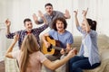 A group of friends with a guitar sing songs at a party indoor Royalty Free Stock Photo