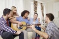 A group of friends with a guitar sing songs at a party indoor Royalty Free Stock Photo