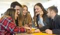 Group of friends hanging out with each other sitting in a bar using their mobile phones - Young people , millennial holding Royalty Free Stock Photo