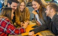 Group of friends hanging out with each other sitting in a bar using their mobile phones - Young people , millennial holding Royalty Free Stock Photo