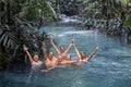 A group of friends happily posing in a beautiful blue river, Waigeo Island, Indonesia