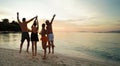 Group of friends having fun on the beach during sunset, having fun and jumping. Young people enjoying summer vacation Royalty Free Stock Photo