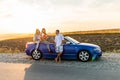 Group of friends having fun in convertible car during road trip at sunset. Young travel people driving a cabriolet during summer Royalty Free Stock Photo