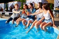 Group of friends having fun at poolside party clinking glasses with fresh cocktails sitting by swimming pool on sunny Royalty Free Stock Photo