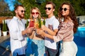 Group of friends having fun at poolside summer party, clinking glasses with colorful summer cocktails outdoors near Royalty Free Stock Photo