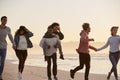 Group Of Friends Having Fun Running Along Winter Beach Together Royalty Free Stock Photo