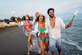 Group of friends having fun running on the beach with sparklers Royalty Free Stock Photo