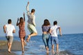 Group of friends having fun walking down the beach at sunset Royalty Free Stock Photo