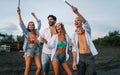 Group of happy friends having fun walking down the beach at sunset Royalty Free Stock Photo