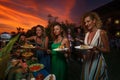 Friends having Ã¢â¬â¹furshet in the backyard at summer sunset. Young women are putting food on a plate