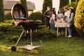 Group of friends having party outdoors. Focus on barbecue grill with food. Space for text Royalty Free Stock Photo