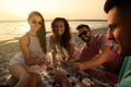 Group of friends having picnic near river at sunset Royalty Free Stock Photo