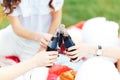 Group of friends holding drinks at the summer picnic. Close up. Make chears black lemonade in glass bottles