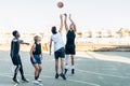 Group of friends jumping as playing basketball in an outdoors court