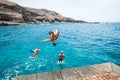 Group of friends jumping off together at the beach doing flips and having fun in the water - people enjoyinng thei holiday at the Royalty Free Stock Photo