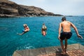 Group of friends jumping off together at the beach doing flips and having fun in the water - people enjoyinng thei holiday at the Royalty Free Stock Photo