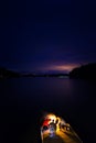 A group of friends lighting fireworks off on a dock by the lake at night.