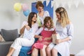 Group of friends in the living room with a baby presents celebrating baby shower