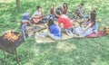 Group of friends making picnic barbecue outdoor in city park - Young people having fun playing music and relaxing at bbq party