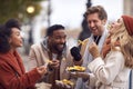 Group Of Friends Outdoors Wearing Coats And Scarves Eating Takeaway Fries In Autumn London Royalty Free Stock Photo