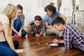 A group of friends play board games on the floor indoors.