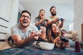 Group of friends play video games together at home