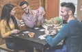 Group of friends playing cards sitting at table inside holidays camping house bungalow - Young happy people having fun laughing Royalty Free Stock Photo