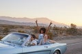 Group Of Friends On Road Trip Driving Classic Convertible Car