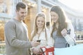 Group Of Friends Shopping In Mall Looking At Mobile Phone Royalty Free Stock Photo