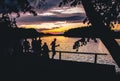 Group of friends silhouette by lake having fun in nature on celebrations. Blank space fun party outdoors