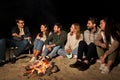 Group of friends sitting at camp fire on beach Royalty Free Stock Photo